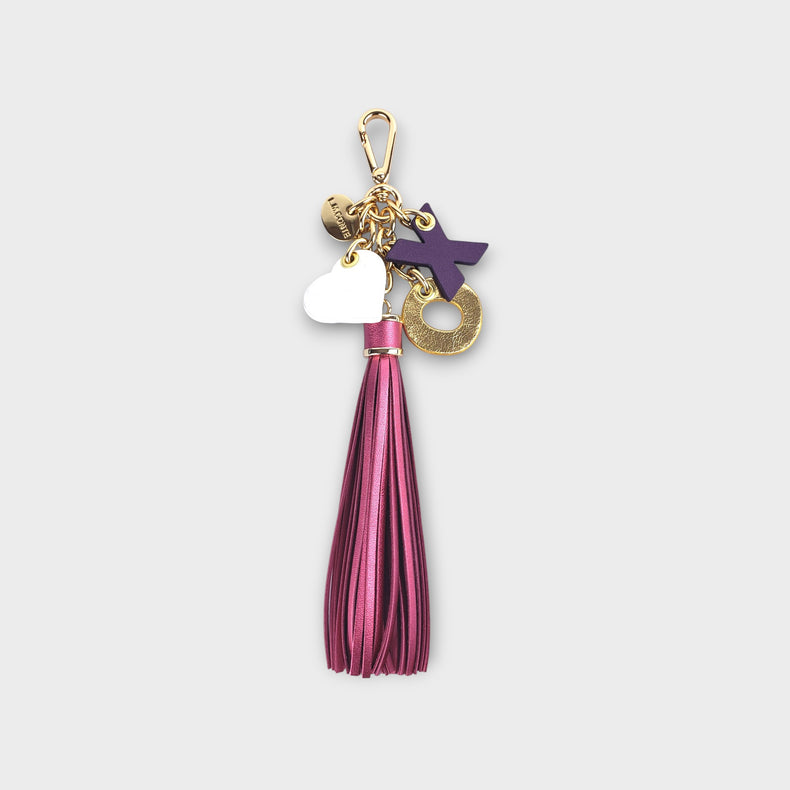 Keychain with pink fringe tassel and colorful X-O letter charms with a heart against a light gray background.