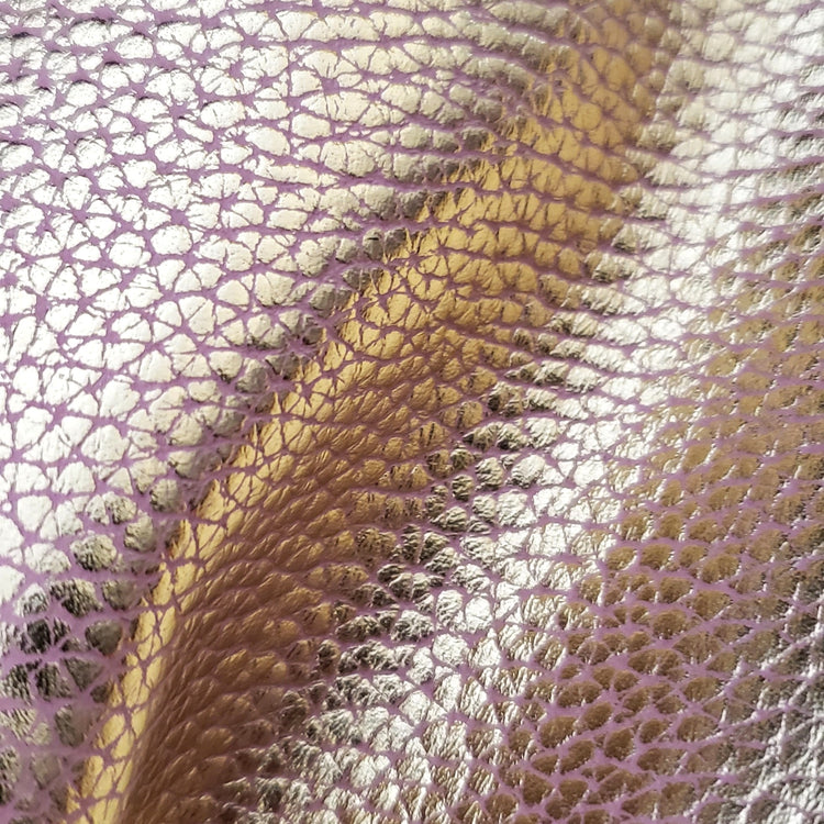 Close-up of a pink leather with heavy grain texture of gold foiling.