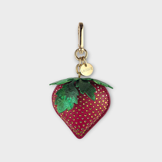 Strawberry-shaped handbag charm with gold hardware on a light gray background.