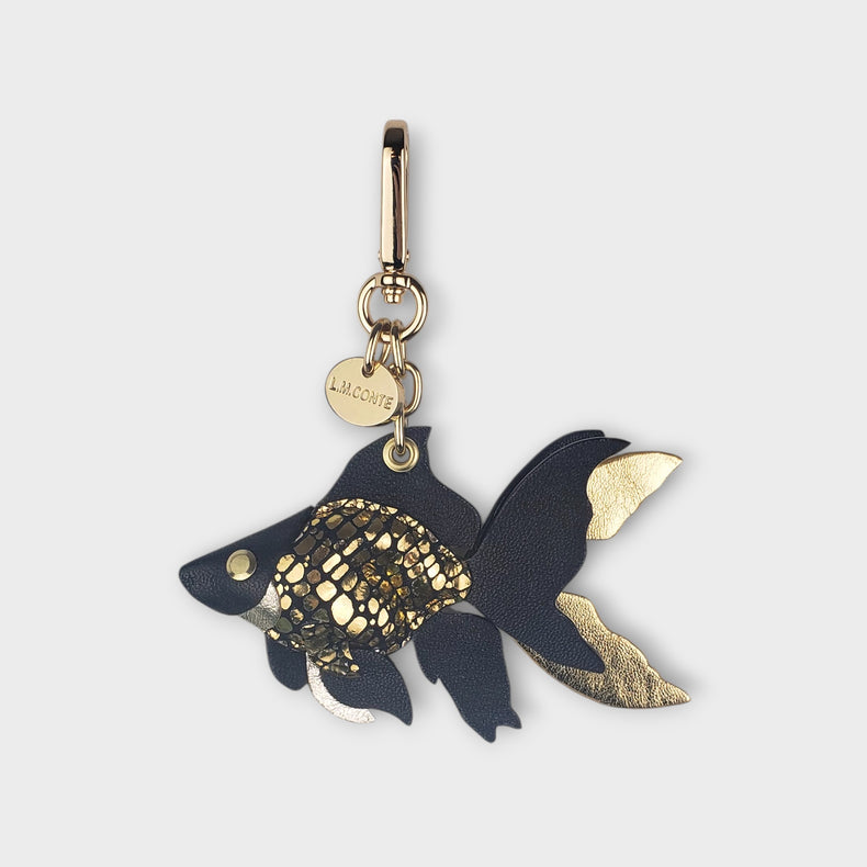 Goldfish-shaped luxury handbag charm with gold accents against a soft gray background.
