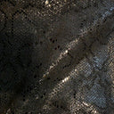 Close-up of a textured surface with dark glossy light reflective patterned scales of a python.