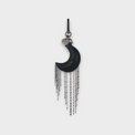 Black crescent moon-shaped handbag charm with dangling hematite bar chain on a gray background.