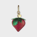 Strawberry-shaped handbag charm with gold hardware on a light gray background.