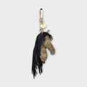 Horse head handbag charm with black heavy fringe as the mane on a light gray background.
