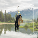 Horse head purse charm with fringe mane against a scenic background of mountains and lake.